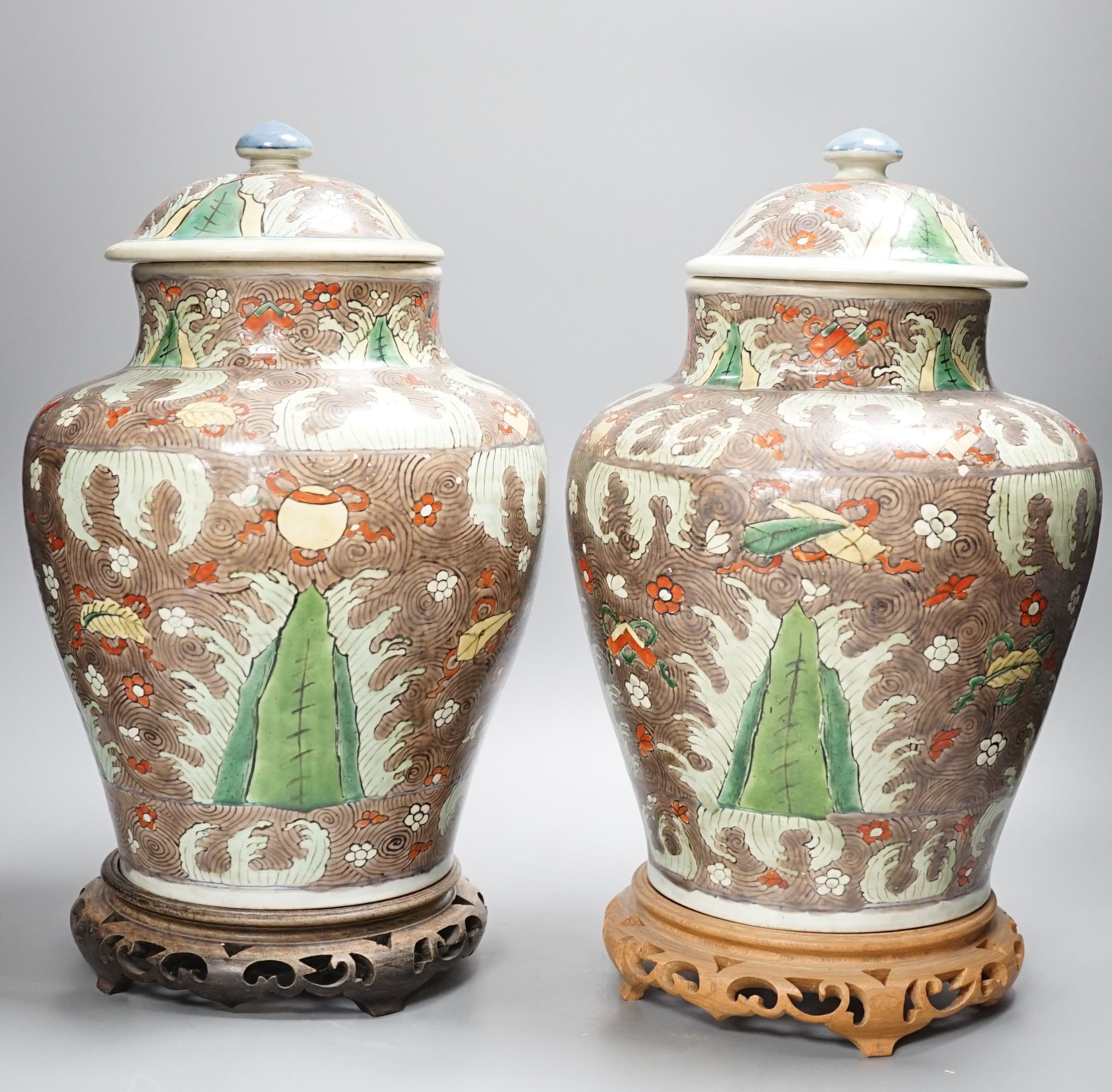 A pair of Chinese enamelled porcelain jars and covers, in Transitional style, 34cm high, wood stands